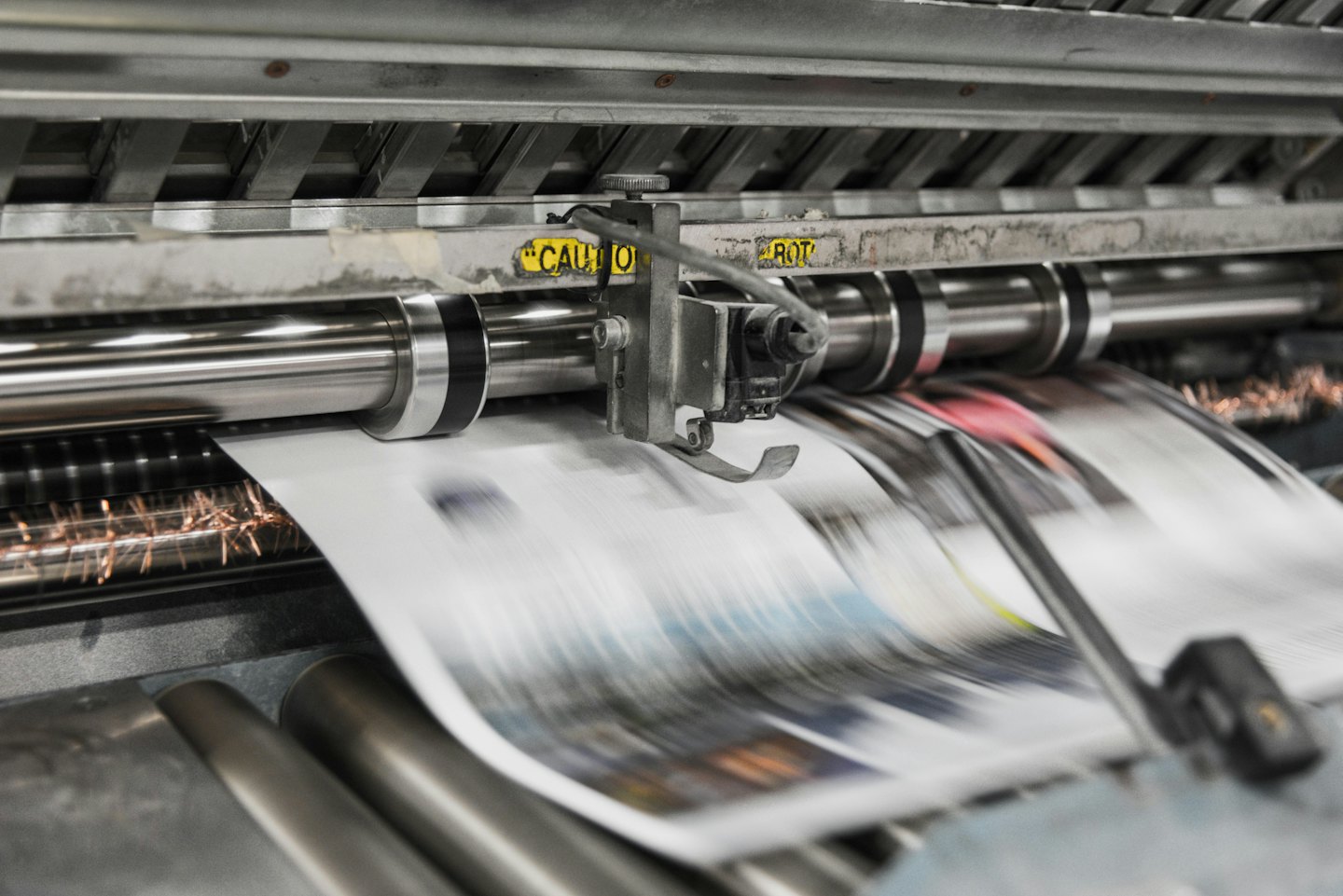 Macchina da stampa che alimenta carta attraverso rulli metallici.
