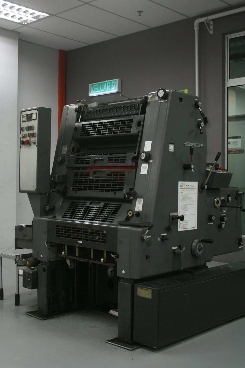Una macchina da stampa offset industriale si trova all'interno di un'officina.
